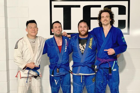 Four men smile for the camera after a tiring BJJ class
