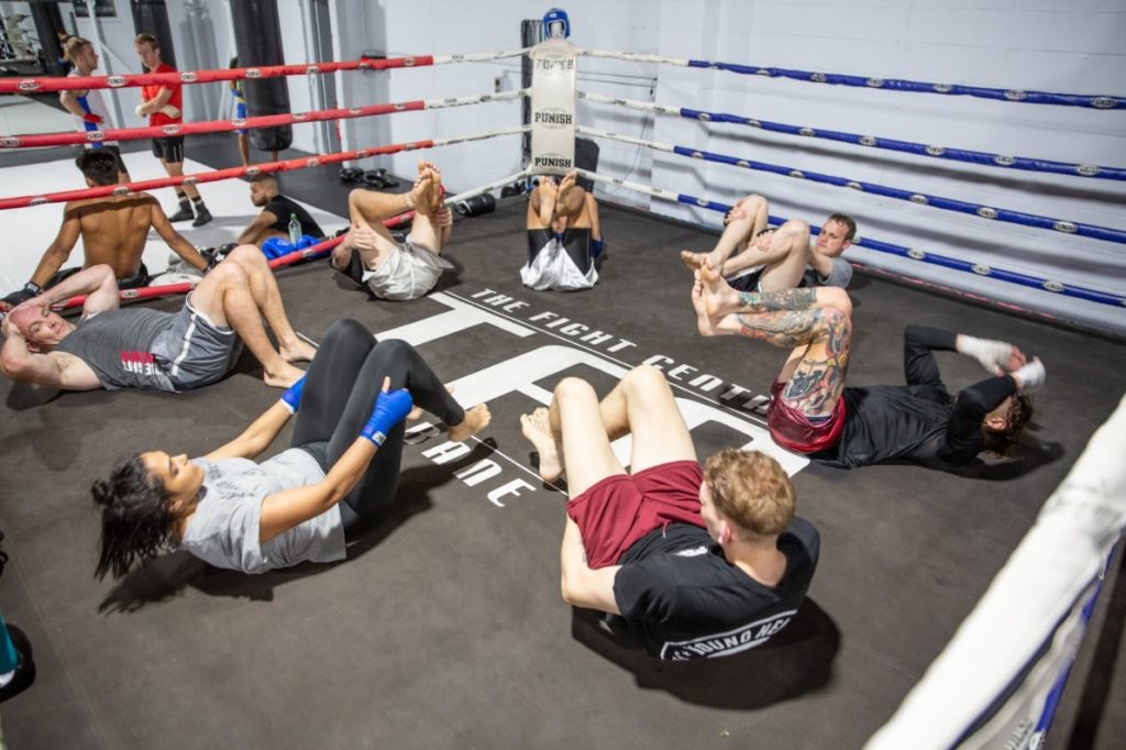 a group of people lying down in a circle, practicing core exercises for martial arts