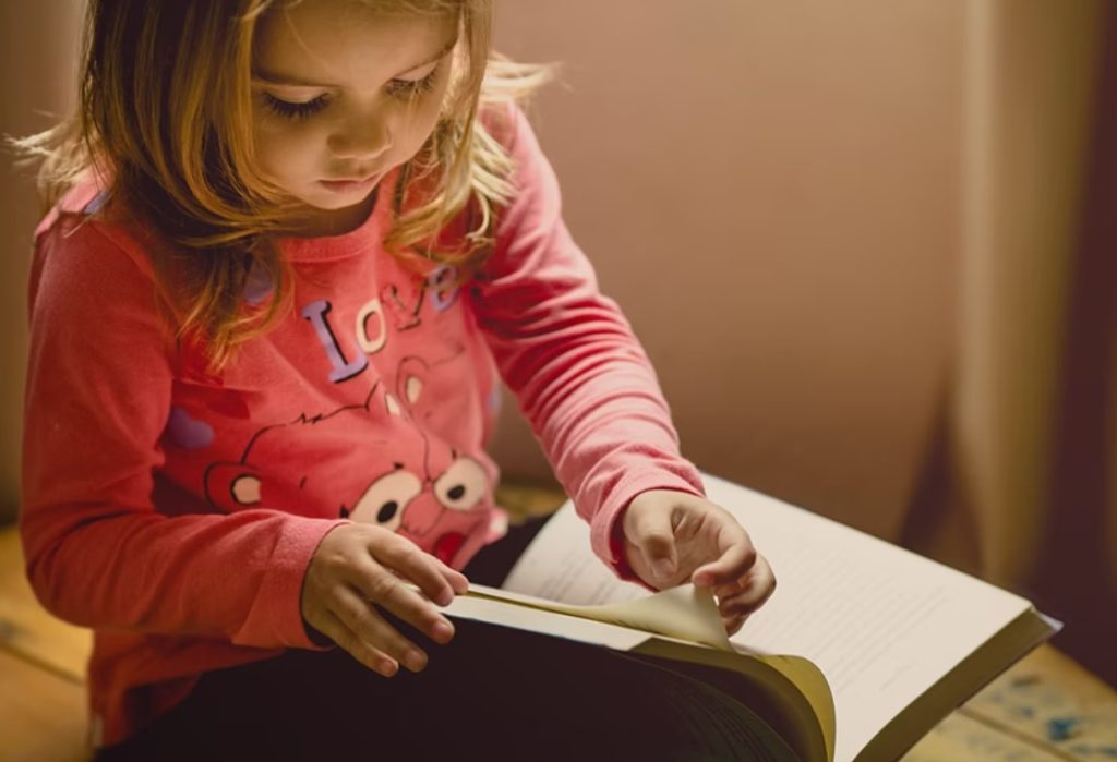 a young girl in pink reads a book