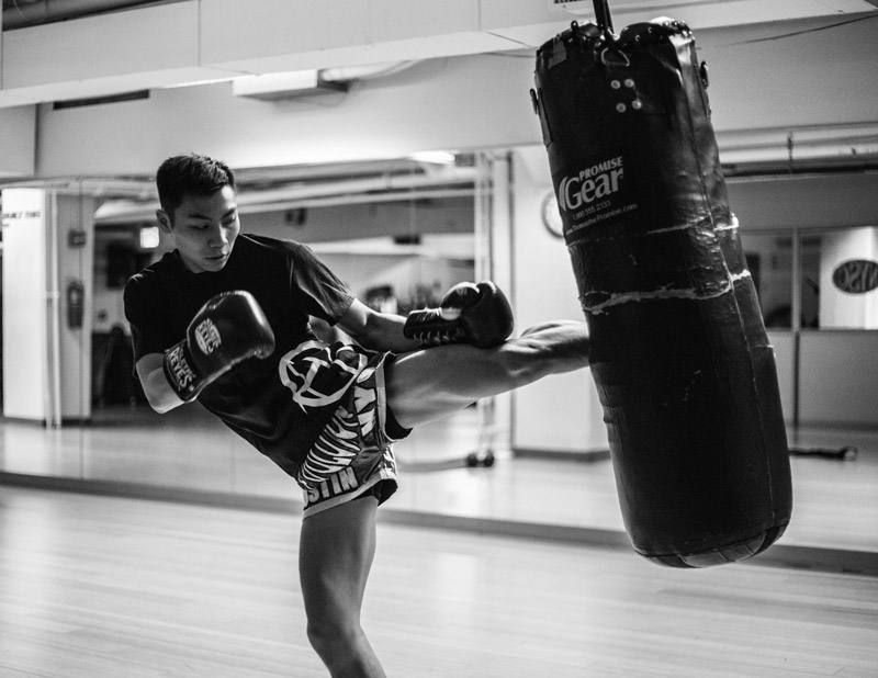 A Muay Thai fighter lands a switch kick on the heavy bag.