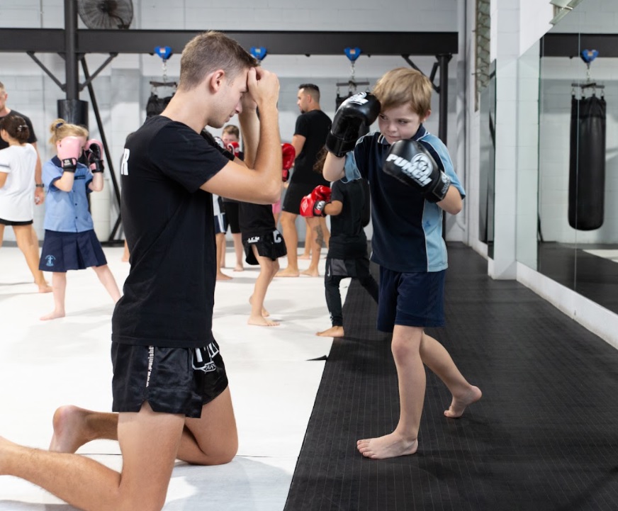 a martial arts teacher teaches a young boy the proper fight stance