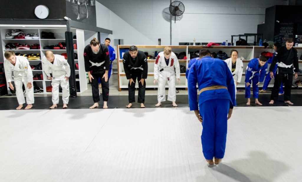a bjj class with students lined up and bowing towards the teacher